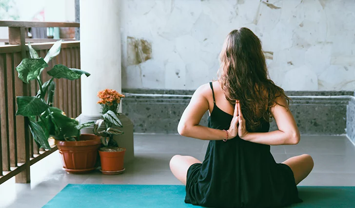 Mujer haciendo yoga en el balcón